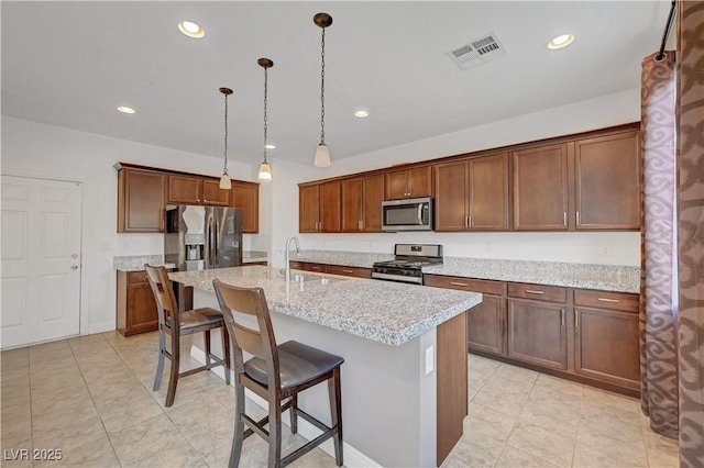 4641 Therapeutic St, North Las Vegas, NV 89031 - kitchen with stainless steel appliances, a breakfast bar area, a center island with sink, recessed lighting, and pendant lighting