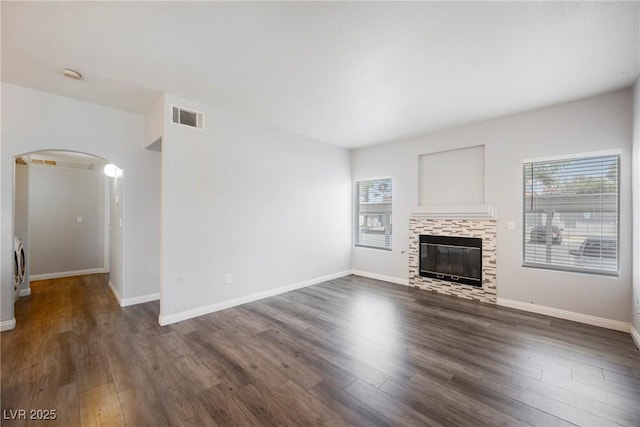 6006 Vegas Dr, Las Vegas, NV 89108 - unfurnished living room featuring arched walkways, plenty of natural light, wood finished floors, and a tiled fireplace