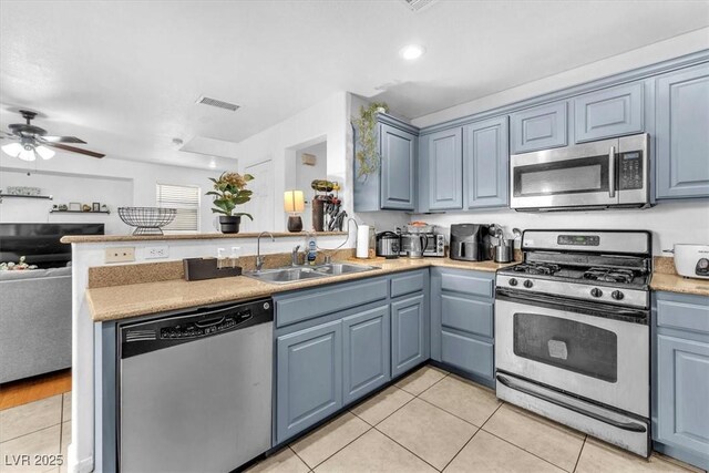 6068 Conroe Ct, Las Vegas, NV 89118 - kitchen featuring stainless steel appliances, light tile patterned floors, a peninsula, open floor plan, and blue cabinets