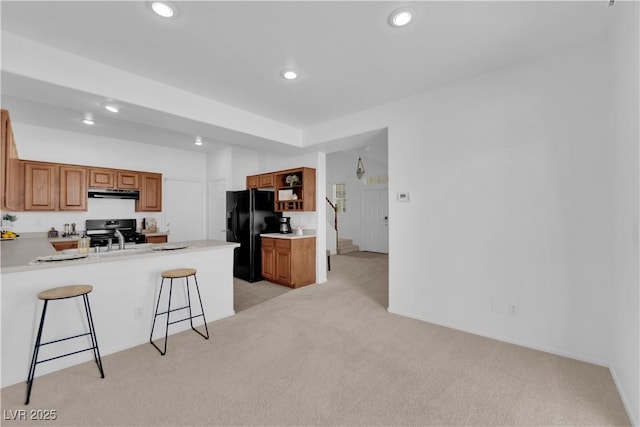 5653 Mount Athos St, North Las Vegas, NV 89031 - kitchen featuring black refrigerator with ice dispenser, under cabinet range hood, light colored carpet, stove, and recessed lighting