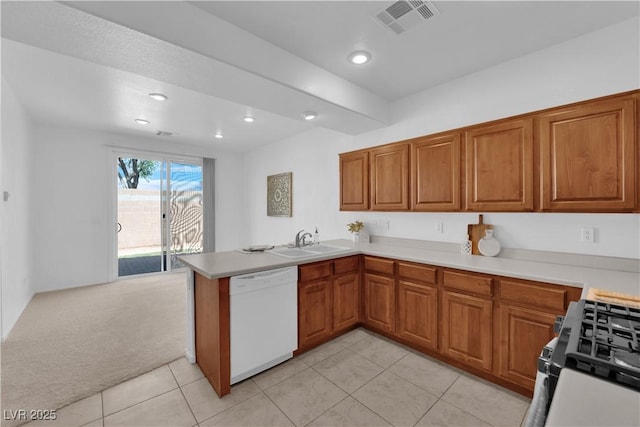 5653 Mount Athos St, North Las Vegas, NV 89031 - kitchen with white dishwasher, brown cabinets, light colored carpet, a peninsula, and range with gas stovetop
