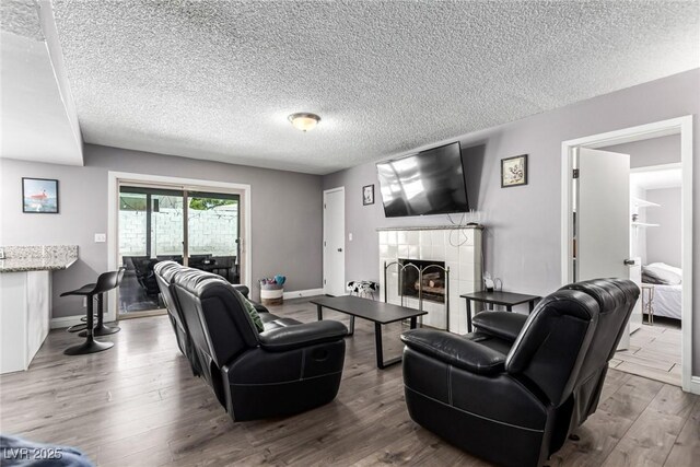 3158 Brockington Dr, Las Vegas, NV 89120 - living room featuring a textured ceiling, wood finished floors, and a tiled fireplace