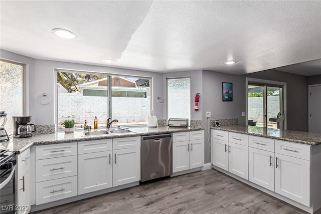 3158 Brockington Dr, Las Vegas, NV 89120 - kitchen featuring appliances with stainless steel finishes, a peninsula, stone countertops, light wood-style flooring, and a textured ceiling