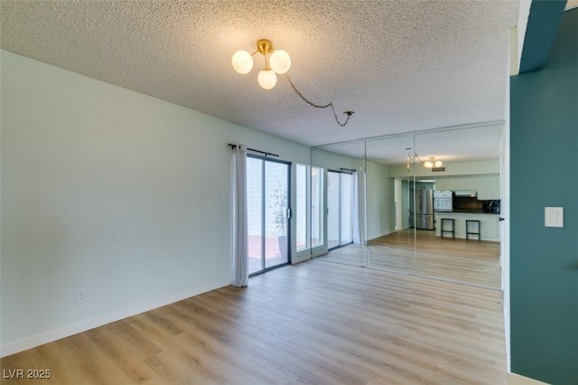 3785 Decade St, Las Vegas, NV 89121 - empty room with light wood-style floors, a chandelier, and a textured ceiling