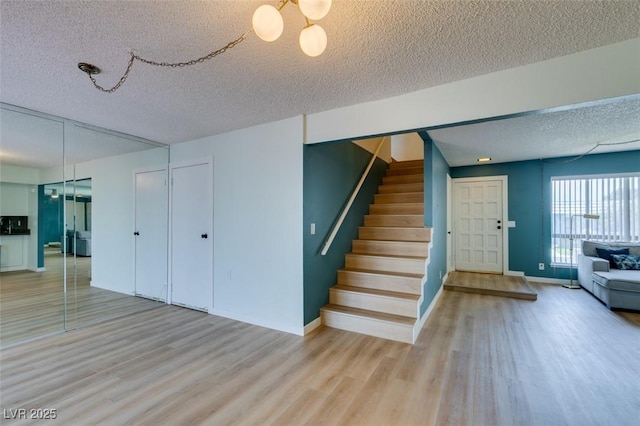 3785 Decade St, Las Vegas, NV 89121 - unfurnished living room featuring a textured ceiling, light wood-type flooring, stairs, and a chandelier