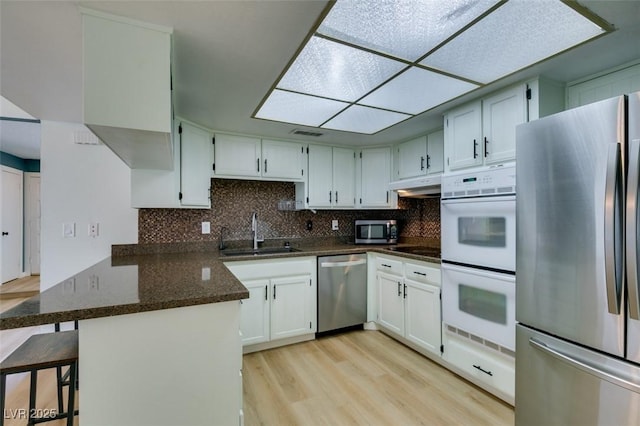 3785 Decade St, Las Vegas, NV 89121 - kitchen with stainless steel appliances, a peninsula, under cabinet range hood, light wood-type flooring, and decorative backsplash