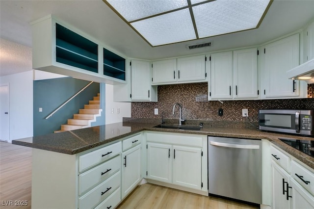 3785 Decade St, Las Vegas, NV 89121 - kitchen with appliances with stainless steel finishes, light wood finished floors, white cabinetry, and tasteful backsplash