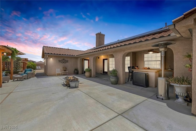 9015 S Tenaya Way, Las Vegas, NV 89113 - back of house at dusk with a fire pit, a chimney, a patio, and solar panels