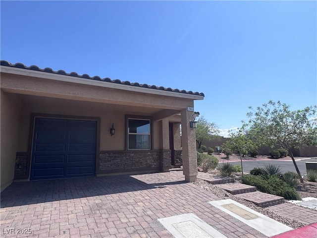 2653 Crystal Blue St, Laughlin, NV 89029 - view of exterior entry featuring stucco siding, stone siding, a garage, a tiled roof, and driveway