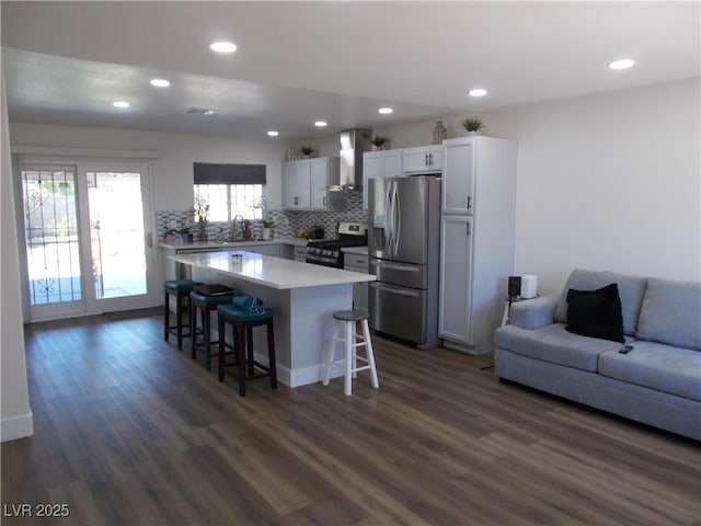 2211 Chipplegate Way N, Las Vegas, NV 89032 - kitchen with stainless steel appliances, wall chimney range hood, open floor plan, a breakfast bar, and dark wood-type flooring