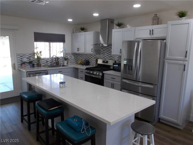 2211 Chipplegate Way N, Las Vegas, NV 89032 - kitchen with appliances with stainless steel finishes, wall chimney range hood, a kitchen breakfast bar, light countertops, and recessed lighting