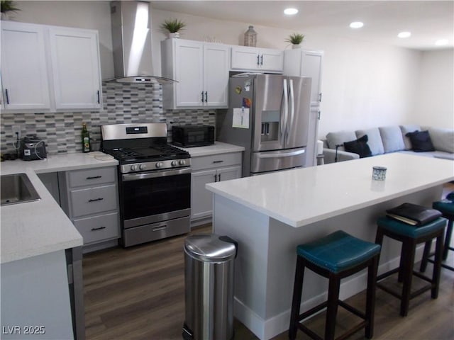 2211 Chipplegate Way N, Las Vegas, NV 89032 - kitchen featuring stainless steel appliances, wall chimney range hood, a breakfast bar, dark wood finished floors, and decorative backsplash