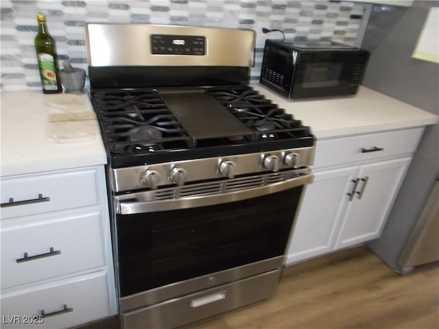 2211 Chipplegate Way N, Las Vegas, NV 89032 - kitchen featuring gas range, black microwave, wood finished floors, white cabinets, and light countertops