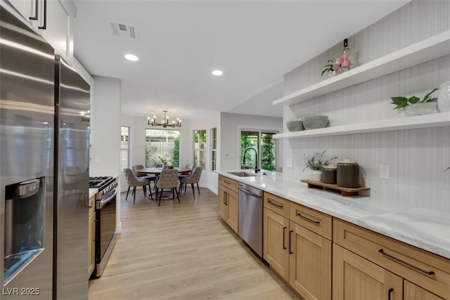 7701 Sea Cliff Way, Las Vegas, NV 89128 - kitchen with stainless steel appliances, a chandelier, light wood-style flooring, open shelves, and light stone counters