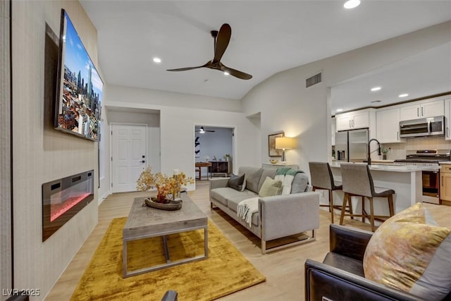 7701 Sea Cliff Way, Las Vegas, NV 89128 - living room with a ceiling fan, recessed lighting, lofted ceiling, a large fireplace, and light wood finished floors