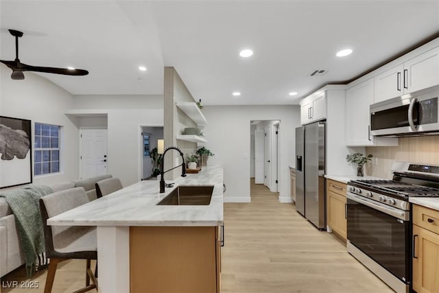 7701 Sea Cliff Way, Las Vegas, NV 89128 - kitchen featuring appliances with stainless steel finishes, open floor plan, light wood finished floors, a breakfast bar, and open shelves
