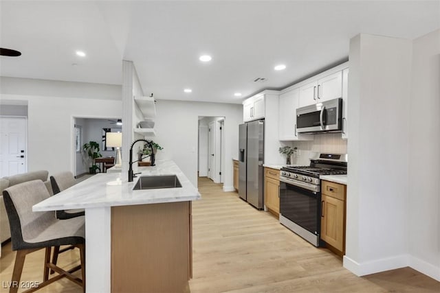 7701 Sea Cliff Way, Las Vegas, NV 89128 - kitchen featuring stainless steel appliances, a kitchen bar, open shelves, light wood finished floors, and recessed lighting