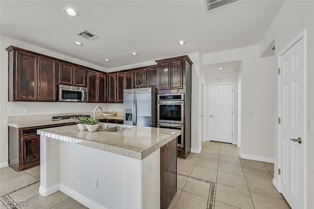 9044 Blue Raven Ave Unit R, Las Vegas, NV 89143 - kitchen featuring appliances with stainless steel finishes, light tile patterned floors, light countertops, recessed lighting, and a center island with sink