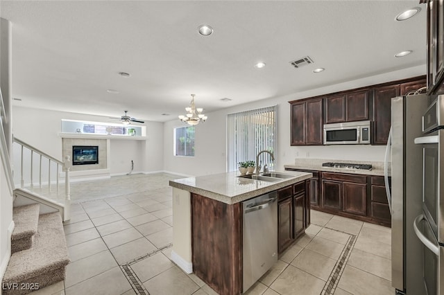 9044 Blue Raven Ave Unit R, Las Vegas, NV 89143 - kitchen featuring stainless steel appliances, light tile patterned flooring, a center island with sink, dark brown cabinets, and recessed lighting