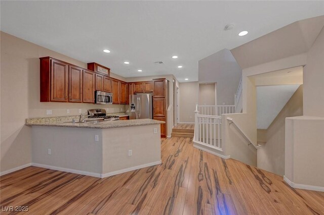 7856 Carysford Ave, Las Vegas, NV 89178 - kitchen featuring appliances with stainless steel finishes, light wood-style flooring, a peninsula, light stone counters, and recessed lighting