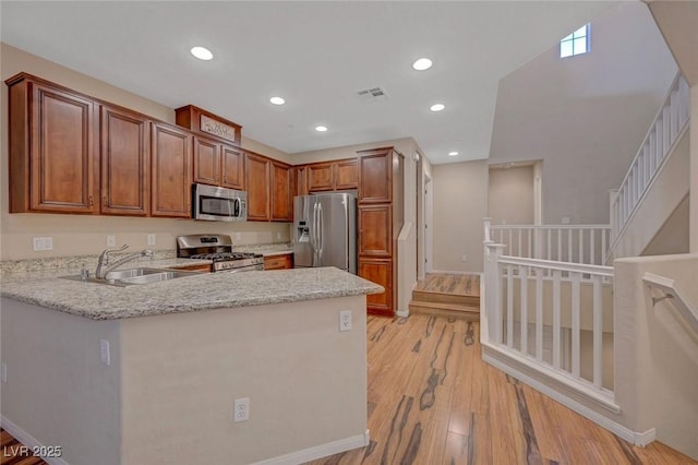 7856 Carysford Ave, Las Vegas, NV 89178 - kitchen with stainless steel appliances, a peninsula, light wood finished floors, recessed lighting, and light stone counters