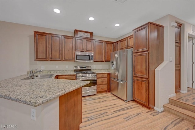 7856 Carysford Ave, Las Vegas, NV 89178 - kitchen featuring stainless steel appliances, a peninsula, light wood-style flooring, recessed lighting, and light stone countertops