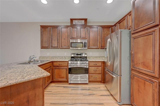 7856 Carysford Ave, Las Vegas, NV 89178 - kitchen featuring stainless steel appliances, a peninsula, light wood-style floors, recessed lighting, and light stone countertops