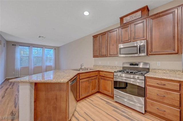 7856 Carysford Ave, Las Vegas, NV 89178 - kitchen with appliances with stainless steel finishes, light wood-style flooring, a peninsula, light stone countertops, and recessed lighting