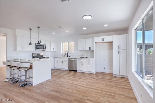 6420 Rosemount Ave, Las Vegas, NV 89156 - kitchen with stainless steel appliances, white cabinetry, light wood-style flooring, decorative light fixtures, and recessed lighting