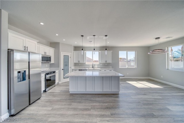 6621 S Parkwood Ct, Pahrump, NV 89061 - kitchen featuring stainless steel appliances, white cabinets, a center island, recessed lighting, and light wood-type flooring