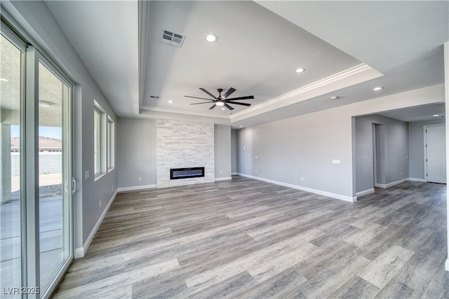 6621 S Parkwood Ct, Pahrump, NV 89061 - unfurnished living room featuring a tray ceiling, ceiling fan, light wood-style floors, recessed lighting, and a large fireplace