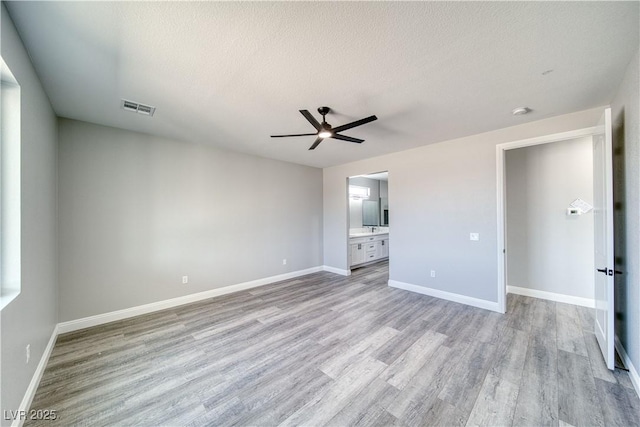 6621 S Parkwood Ct, Pahrump, NV 89061 - unfurnished bedroom featuring light wood finished floors, a textured ceiling, ensuite bathroom, and ceiling fan