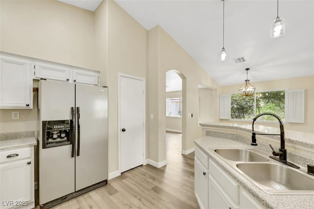 6035 Shadow Oak Dr, North Las Vegas, NV 89031 - kitchen featuring refrigerator with ice dispenser, light wood-style floors, vaulted ceiling, pendant lighting, and white cabinetry