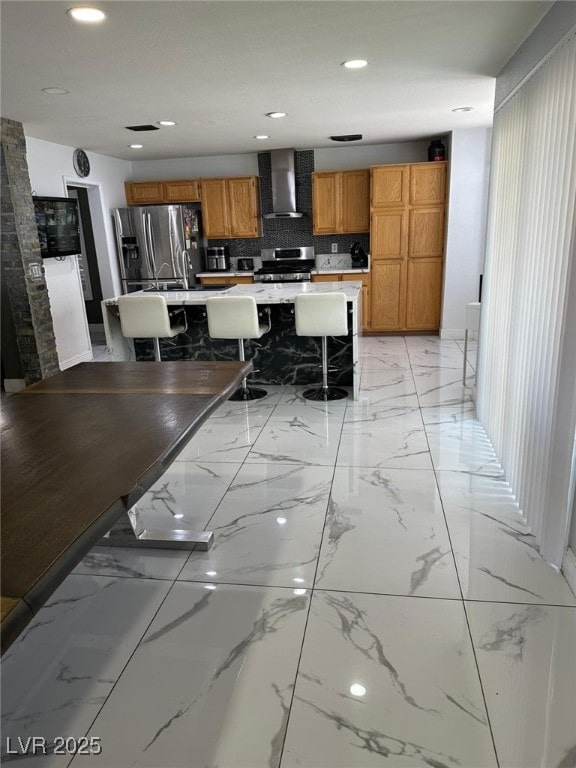 6208 Mandarin Dr, Las Vegas, NV 89108 - kitchen with stainless steel appliances, wall chimney range hood, light countertops, brown cabinets, and light marble finish floors