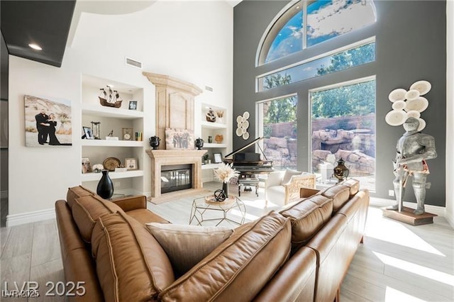 764 Ricota Ct, Henderson, NV 89012 - living room featuring built in features, a high ceiling, a glass covered fireplace, and light wood finished floors