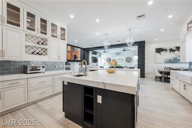 764 Ricota Ct, Henderson, NV 89012 - kitchen featuring decorative backsplash, light wood-style floors, white cabinets, a kitchen island with sink, and recessed lighting