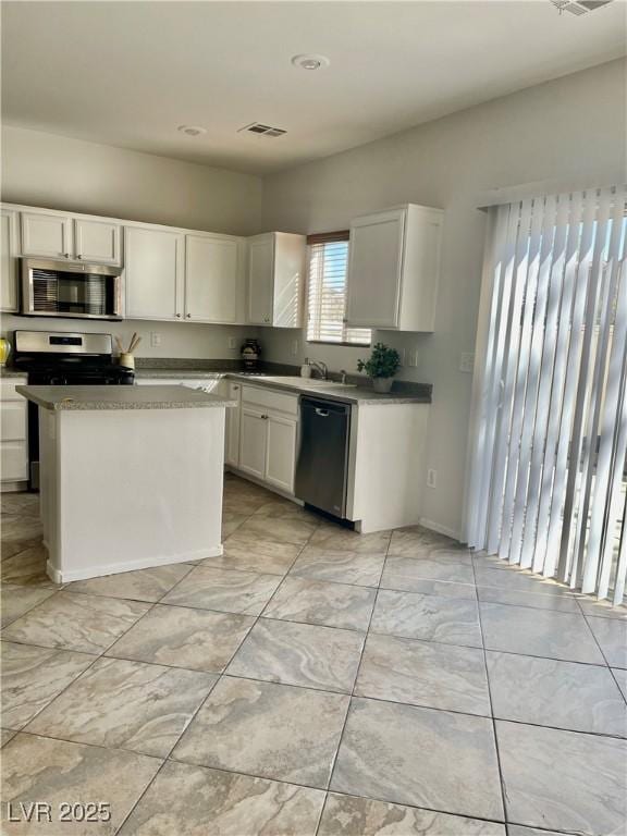908 Shining Rose Pl, Henderson, NV 89052 - kitchen featuring appliances with stainless steel finishes, white cabinets, light marble finish floors, and a kitchen island