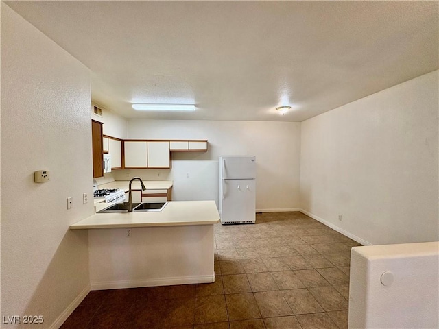 5751 E Hacienda Ave Unit 226, Las Vegas, NV 89122 - kitchen featuring white appliances, a peninsula, light countertops, and dark tile patterned flooring