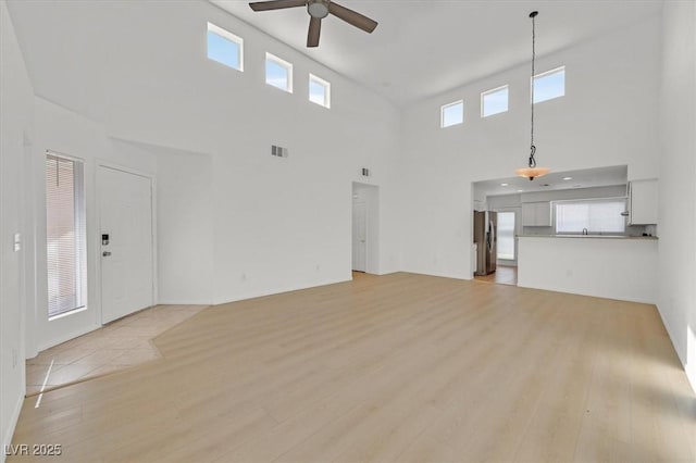 4708 Cohiba Way N, Las Vegas, NV 89031 - unfurnished living room with a ceiling fan, a high ceiling, light wood-style flooring, and healthy amount of natural light