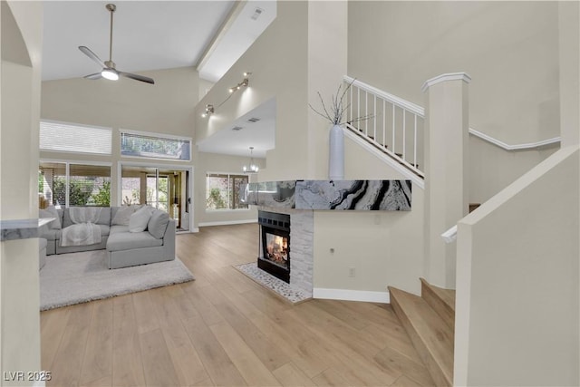 7837 Sea Rock Rd, Las Vegas, NV 89128 - living area featuring high vaulted ceiling, stairs, ceiling fan, wood finished floors, and a multi sided fireplace