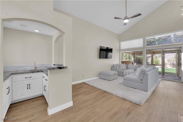 7837 Sea Rock Rd, Las Vegas, NV 89128 - living area with arched walkways, ceiling fan, high vaulted ceiling, and light wood-style floors