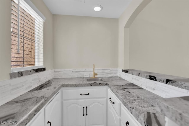 7837 Sea Rock Rd, Las Vegas, NV 89128 - kitchen with white cabinets, light stone countertops, and arched walkways