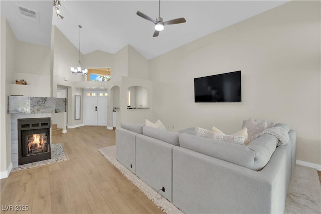 7837 Sea Rock Rd, Las Vegas, NV 89128 - living area featuring high vaulted ceiling, a chandelier, light wood-type flooring, a ceiling fan, and a multi sided fireplace