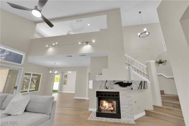 7837 Sea Rock Rd, Las Vegas, NV 89128 - living room with a towering ceiling, a fireplace with flush hearth, wood finished floors, stairway, and a chandelier