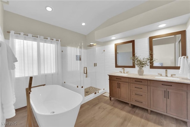 7837 Sea Rock Rd, Las Vegas, NV 89128 - full bathroom with double vanity, a stall shower, a freestanding bath, wood finished floors, and vaulted ceiling
