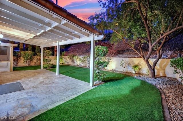 7837 Sea Rock Rd, Las Vegas, NV 89128 - yard at dusk with a fenced backyard and a patio area