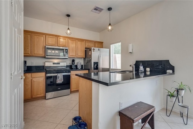 3936 Pepper Thorn Ave Unit 3, North Las Vegas, NV 89081 - kitchen featuring stainless steel appliances, dark countertops, light tile patterned flooring, a peninsula, and hanging light fixtures