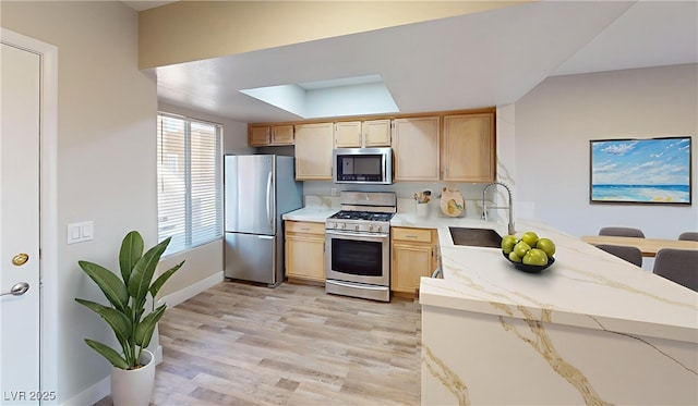 8070 W Russell Rd Unit 1046, Las Vegas, NV 89113 - kitchen with stainless steel appliances, light brown cabinetry, light wood-style flooring, light stone countertops, and a peninsula
