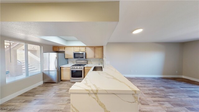 8070 W Russell Rd Unit 1046, Las Vegas, NV 89113 - kitchen featuring appliances with stainless steel finishes, light wood-style flooring, light stone countertops, light brown cabinetry, and a raised ceiling