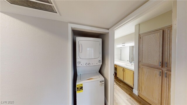 8070 W Russell Rd Unit 1046, Las Vegas, NV 89113 - laundry room with stacked washer and clothes dryer and light wood-type flooring